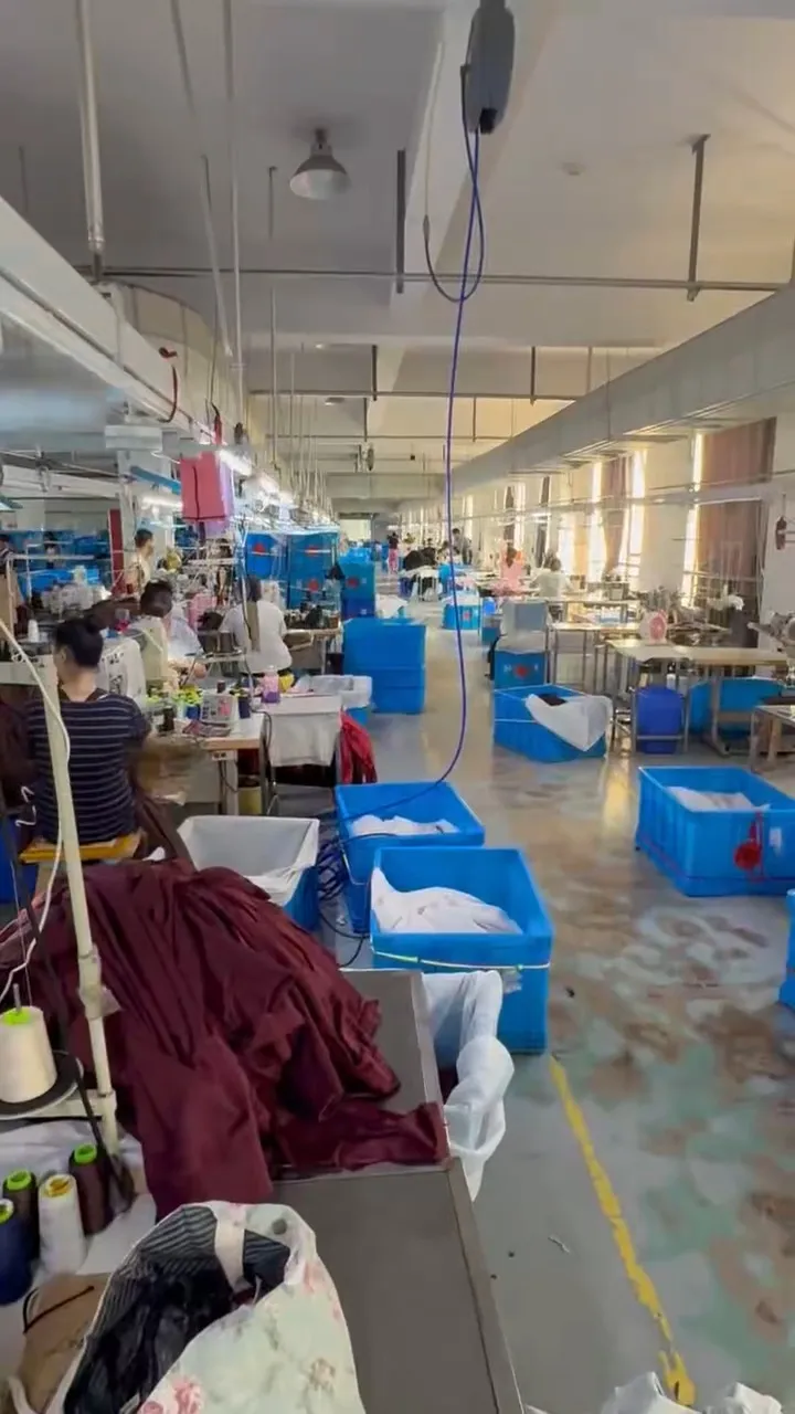 Salle de couture avec rangées de postes le long d’une allée centrale